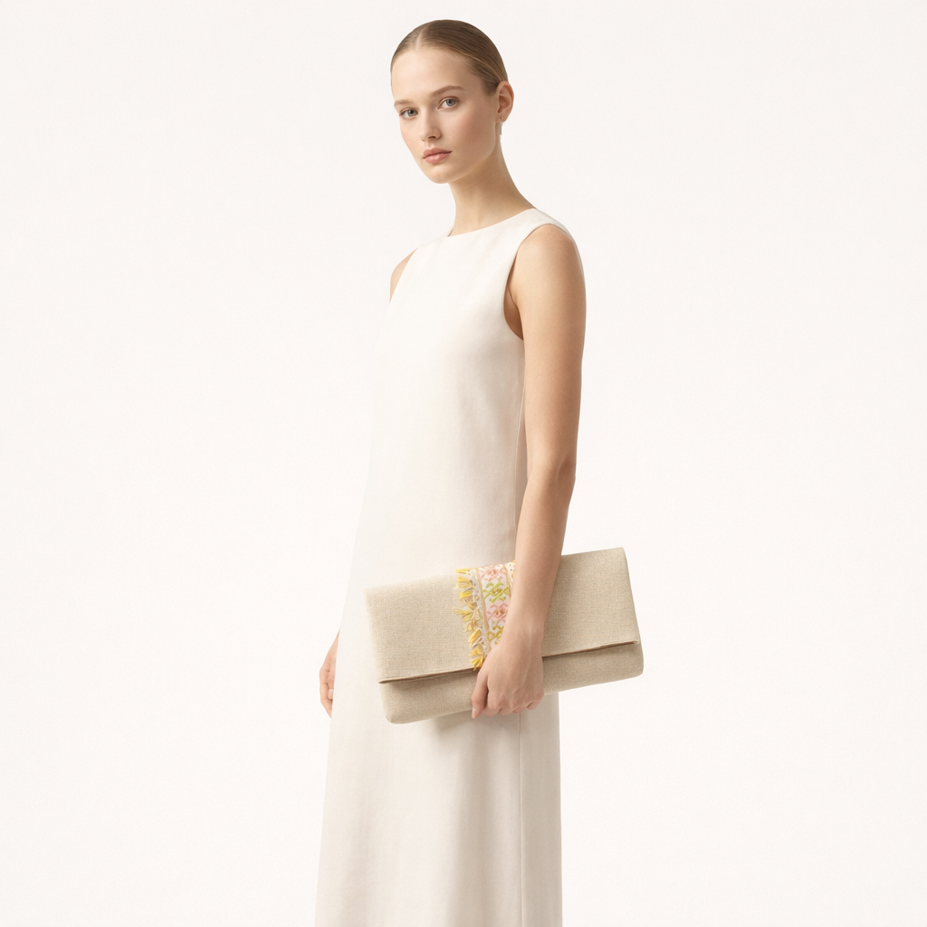 Woman holding a beige clutch with embroidery against a white background