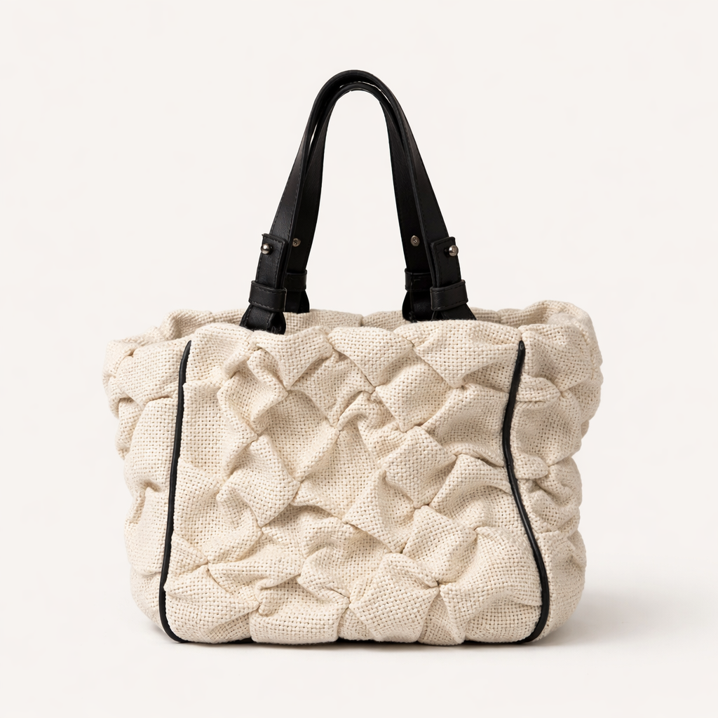 Handbag with black leather handles and trim on a white background