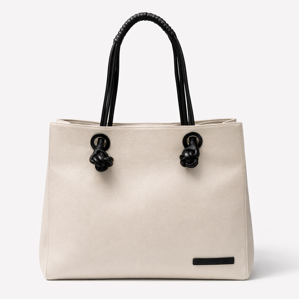 Ivory handbag with black leather handles on a white background